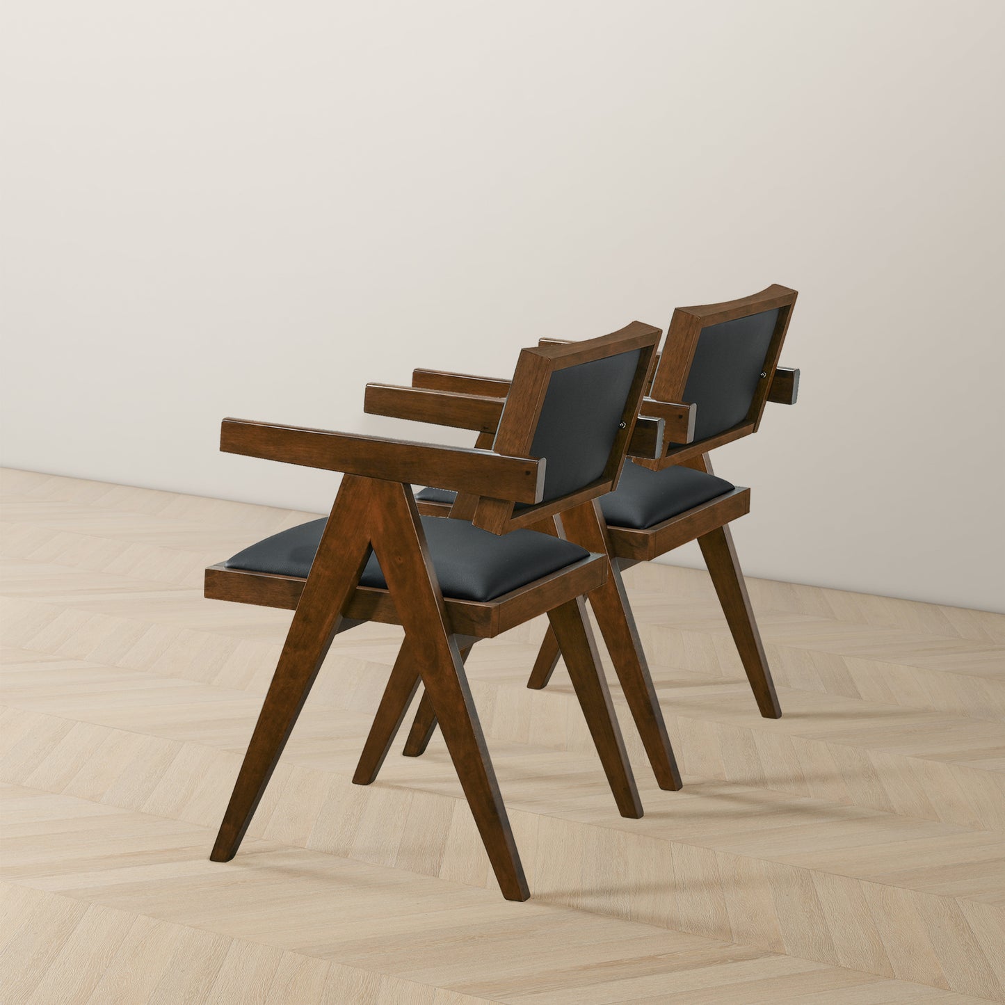 Pair of modern wooden chairs with black cushions on light wood floor, FredCo International furniture