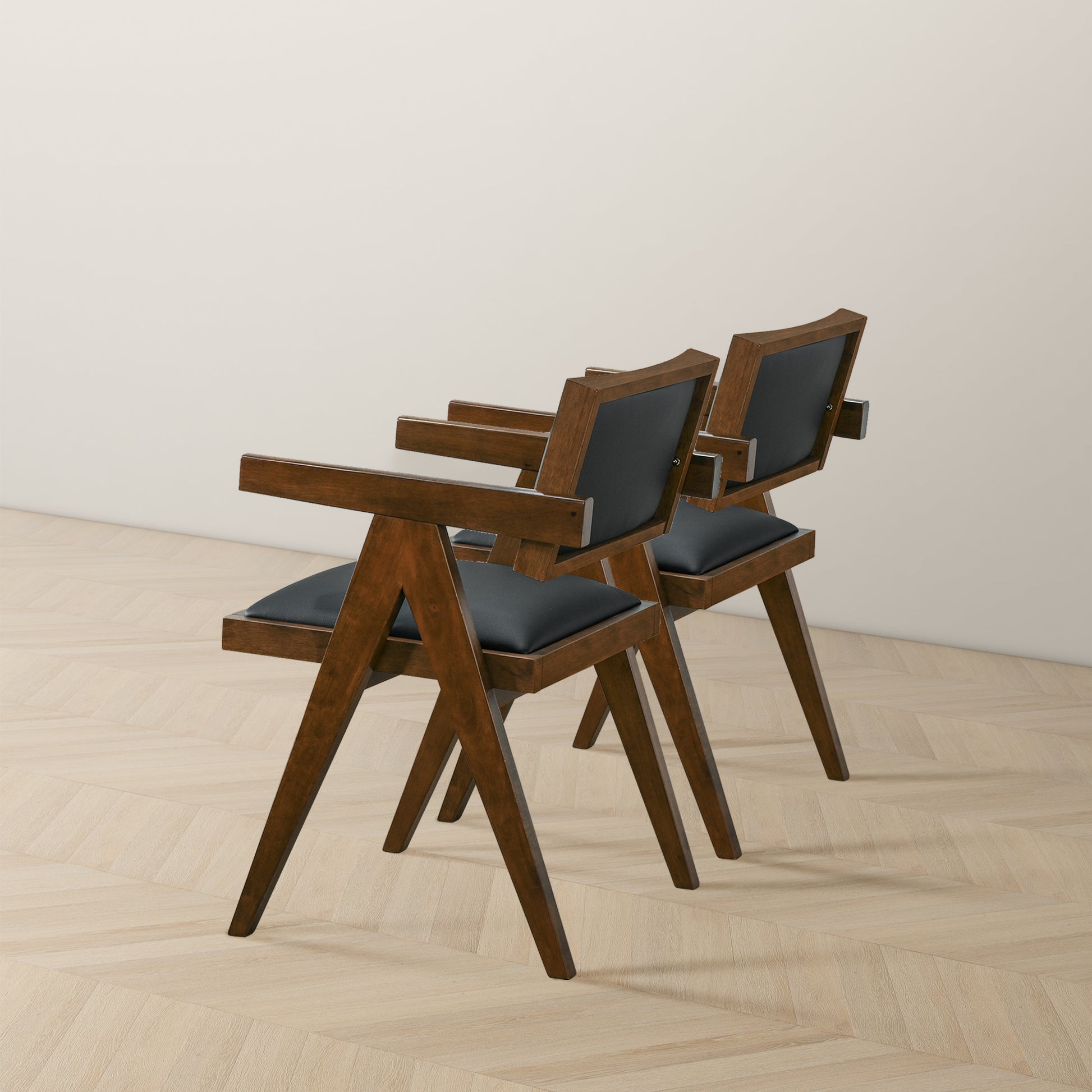 Pair of modern wooden chairs with black cushions on light wood floor, FredCo International furniture