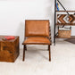 Modern tan leather accent chair on cream rug with wood side table and shelf, FredCo International furniture