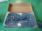 Packaged furniture part in plastic wrap inside an open box on green floor, FredCo International