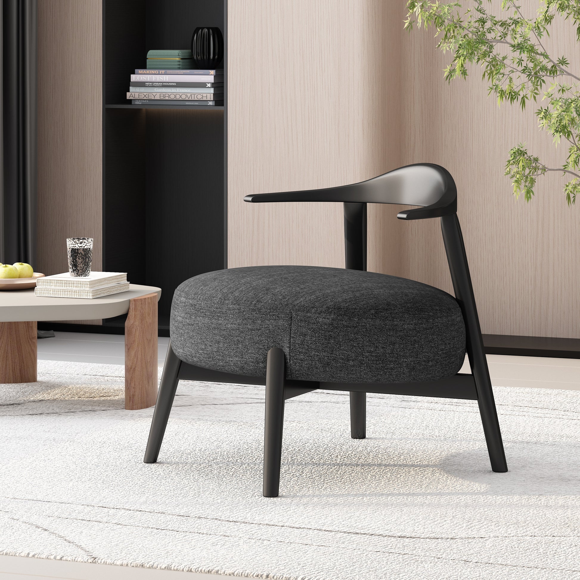 Modern black accent chair in a stylish living room with light wood paneling, books, and coffee table
