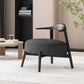 Modern black accent chair in a stylish living room with light wood paneling, books, and coffee table